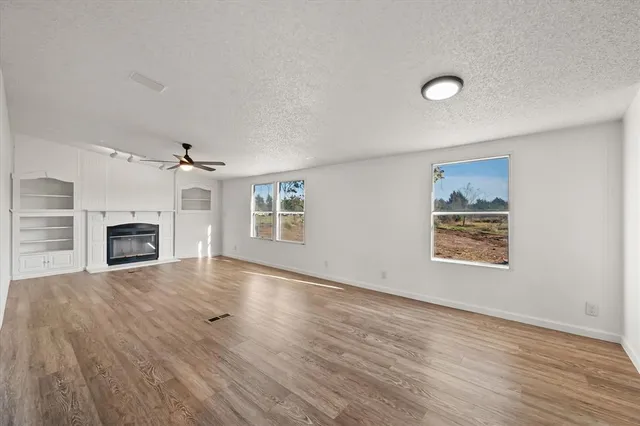 an empty room with windows and fireplace