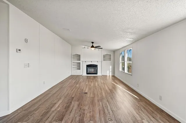 a view of an empty room with a fireplace and a window