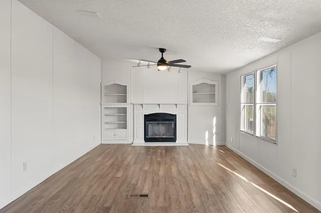 an empty room with windows fireplace and wooden floor