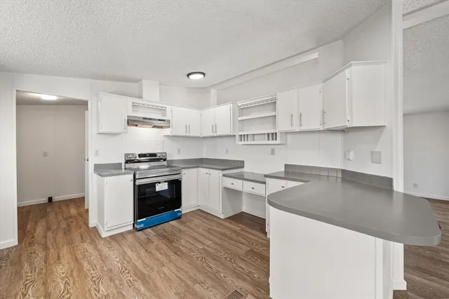 a kitchen with a sink a stove top oven and white cabinets