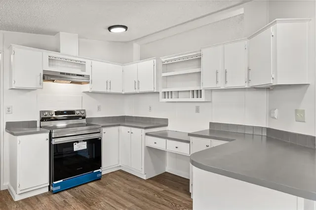 a kitchen with stainless steel appliances granite countertop a sink stove and white cabinets