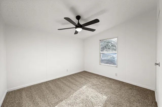 an empty room with a window and a fan