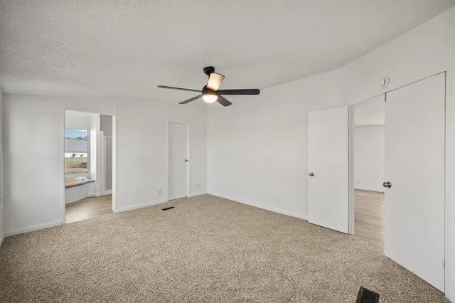 a view of a livingroom with a chandelier fan and windows