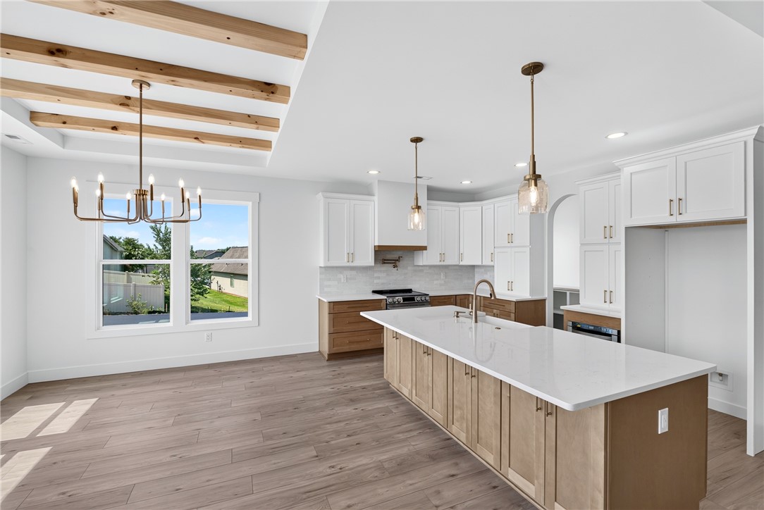 416 Blume Road Anderson, SC 29625 - Photo 8 of 29 A contemporary kitchen features an expansive island and high ceilings with exposed beams, illuminated by large windows.