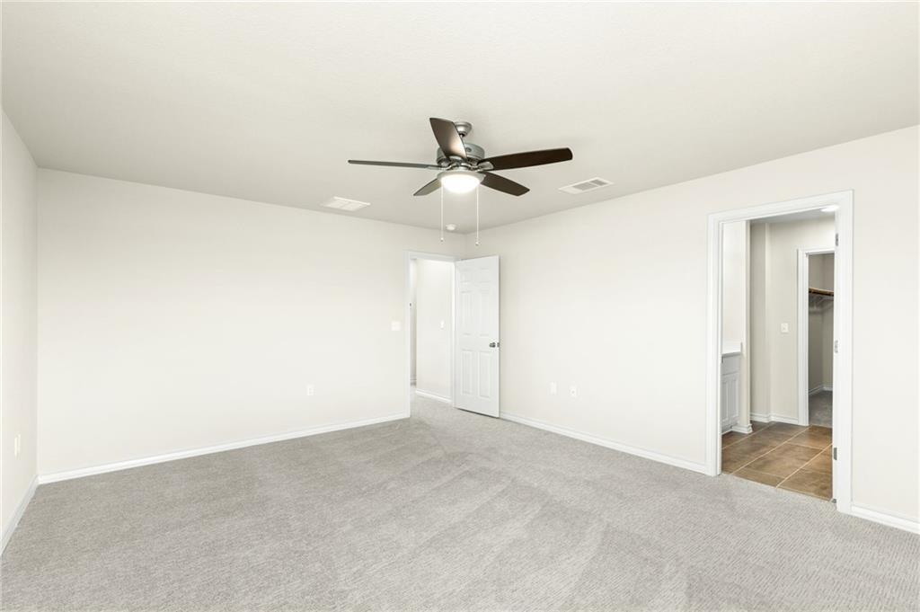 1624 Caballo Blanco Road Austin, TX 78725 - Photo 14 of 23 Well-appointed bedroom with plush carpeting and a modern ceiling fan.