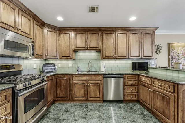 a kitchen with stainless steel appliances granite countertop a stove a sink dishwasher and a microwave