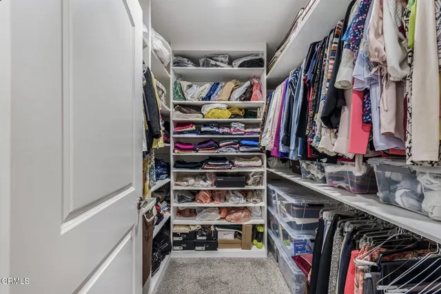 a view of walk in closet with clothes and shoes