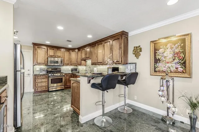 a kitchen with granite countertop a stove a sink and a refrigerator