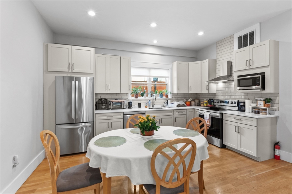 340 Main Street Everett, MA 02149 - Photo 32 of 42 a kitchen with stainless steel appliances granite countertop a dining table chairs refrigerator and microwave