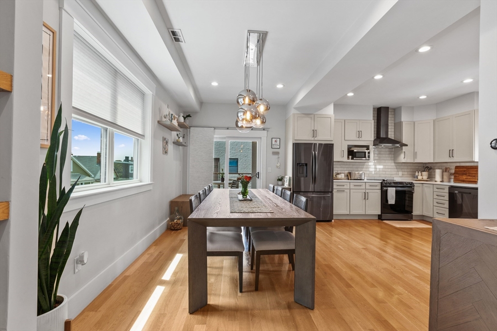 340 Main Street Everett, MA 02149 - Photo 7 of 42 a kitchen with kitchen island granite countertop a refrigerator a stove a sink a dining table and chairs with wooden floor