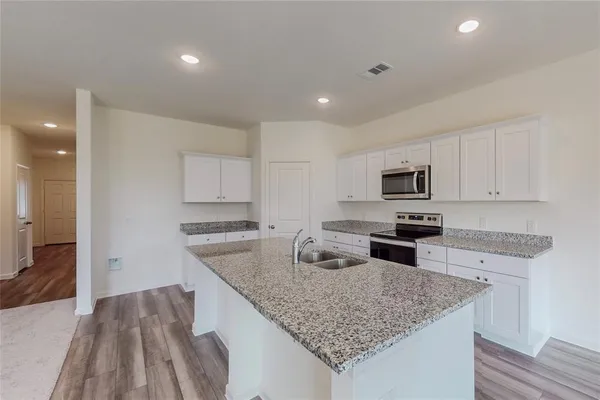 a view of kitchen with refrigerator and white cabinets