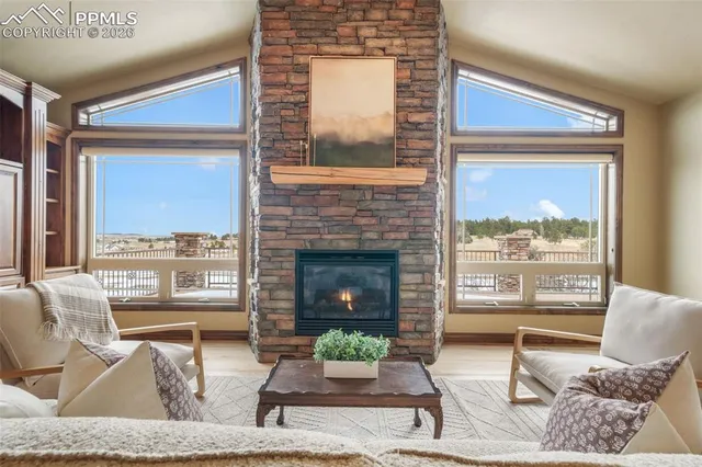 a living room with furniture a fireplace and a floor to ceiling window