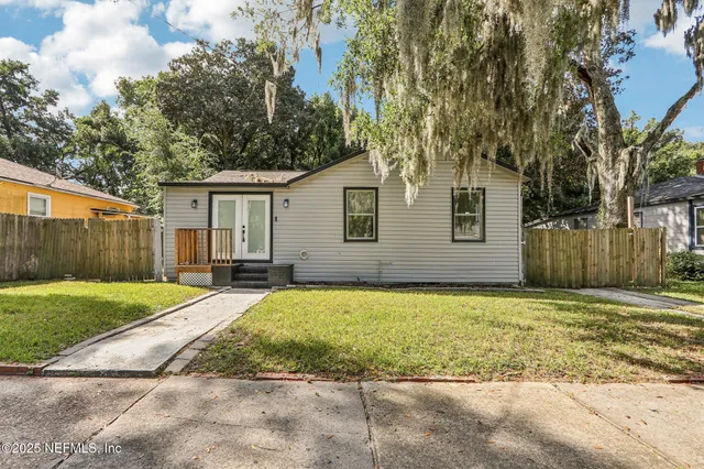 a view of a house with a yard and large tree