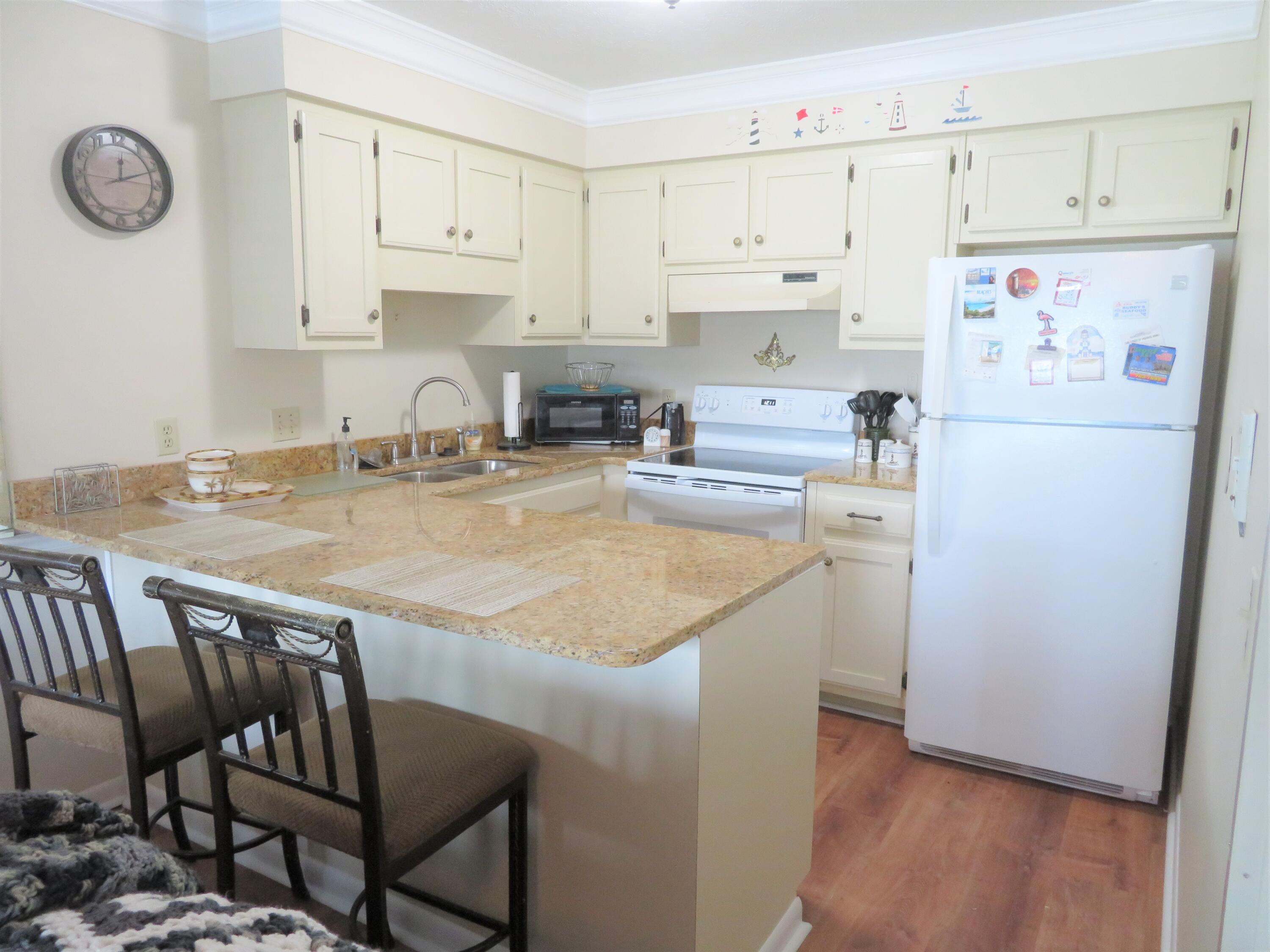 17670 Front Beach Road, Unit B4 Panama City Beach, FL 32413 - Photo 2 of 14 a kitchen with a refrigerator a stove a sink dishwasher and white cabinets with wooden floor