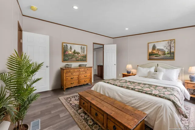 a bedroom with a large bed a painting and potted plant