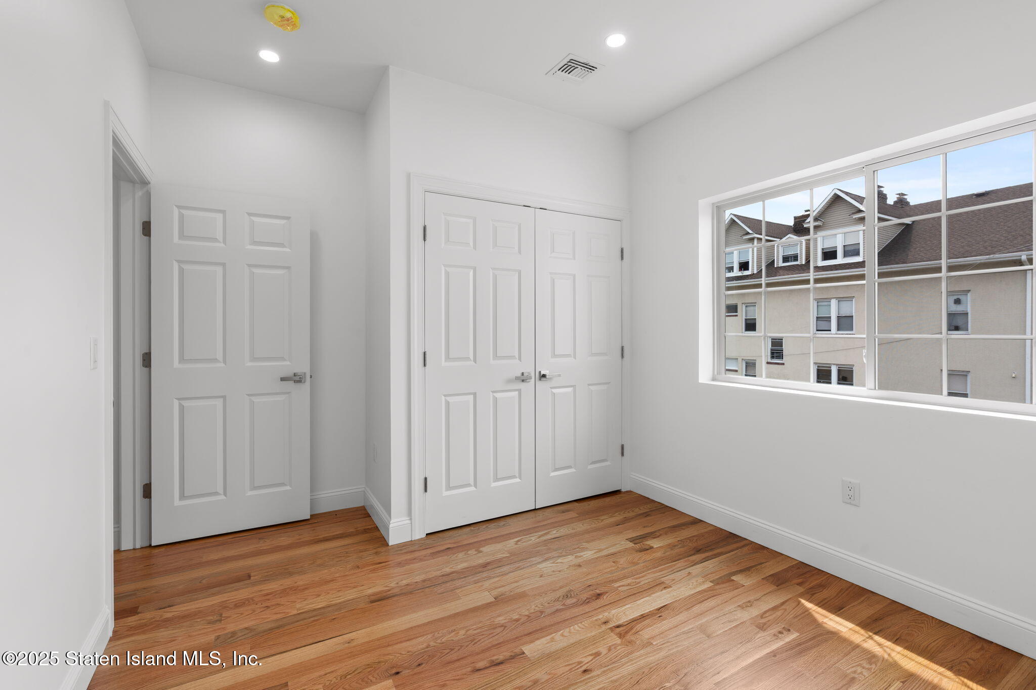 1384 Clove Road Staten Island, NY 10301 - Photo 14 of 51 a view of an empty room with window and wooden floor