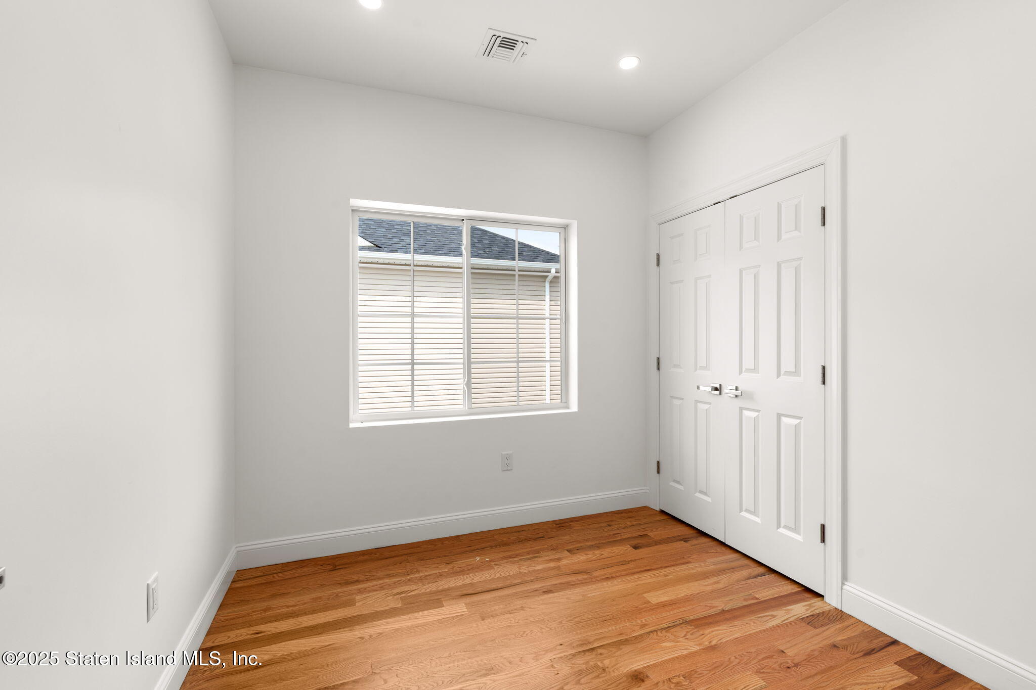 1384 Clove Road Staten Island, NY 10301 - Photo 16 of 51 an empty room with wooden floor and windows