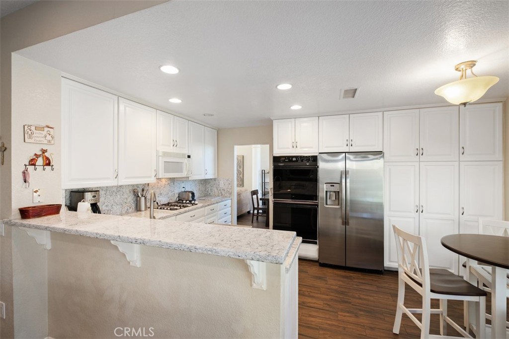20891 Porter Ranch Road Rancho Santa Margarita, CA 92679 - Photo 11 of 40 a kitchen with stainless steel appliances granite countertop a refrigerator a sink a stove a dining table and chairs