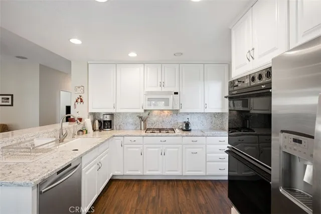 a kitchen with a sink white cabinets and stainless steel appliances