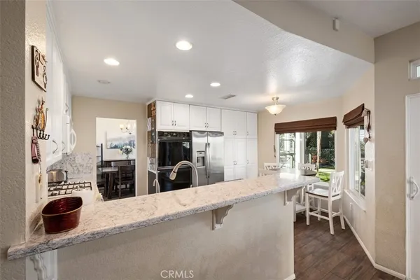 a kitchen with stainless steel appliances kitchen island granite countertop a refrigerator and a sink