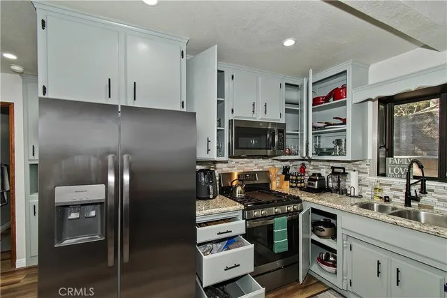 a kitchen with stainless steel appliances granite countertop a stove a sink and a microwave