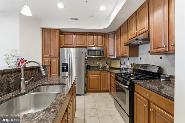 a kitchen with granite countertop a sink stainless steel appliances and cabinets