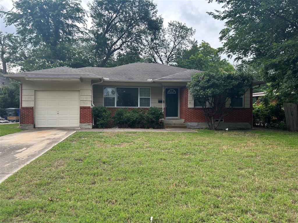 View of front of property featuring an attached garage, concrete driveway, a front yard, and brick siding