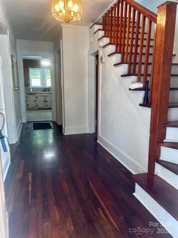 a view of a hallway with wooden floor and a bathroom