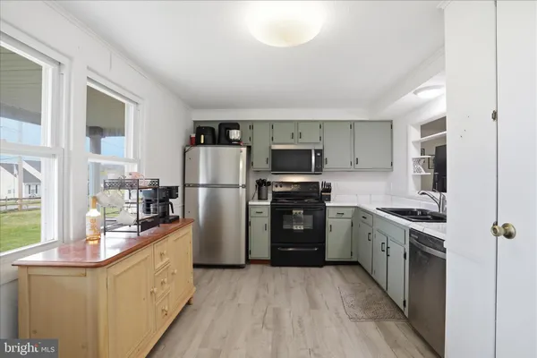 a kitchen with a refrigerator a stove top oven and cabinets