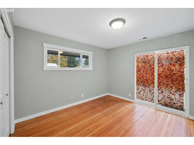 a view of an empty room with window and wooden floor
