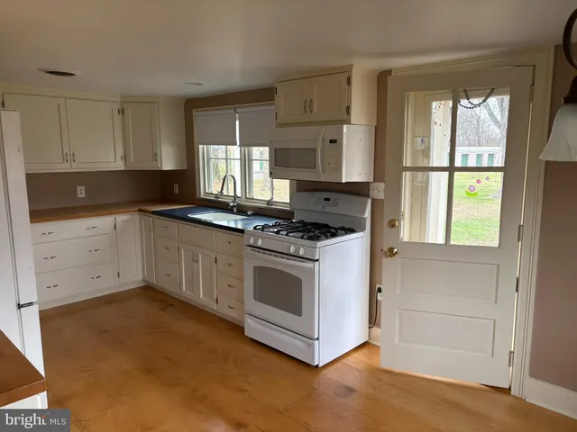 a kitchen with granite countertop white cabinets and white appliances