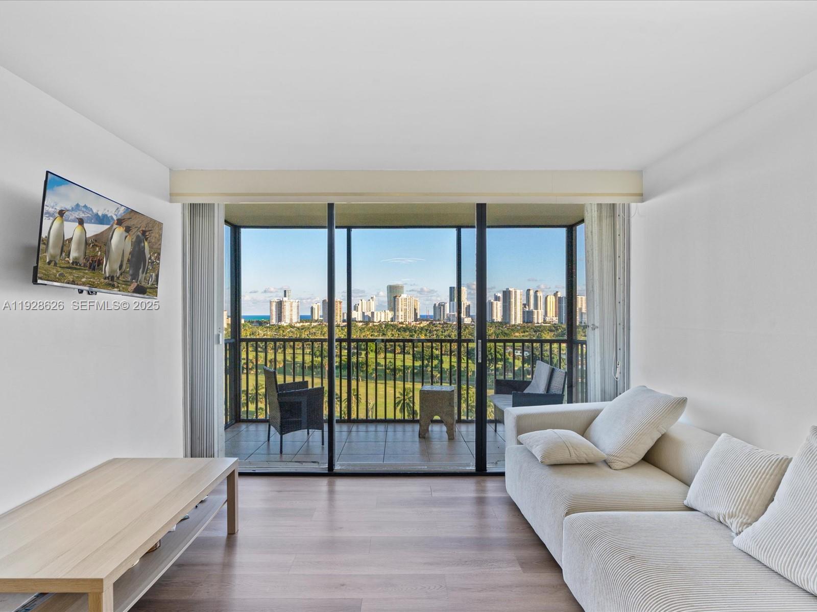 20335 West Country Club Drive, Unit 1608 Aventura, FL 33180 - Photo 2 of 26 a living room with a couch a table and a large window