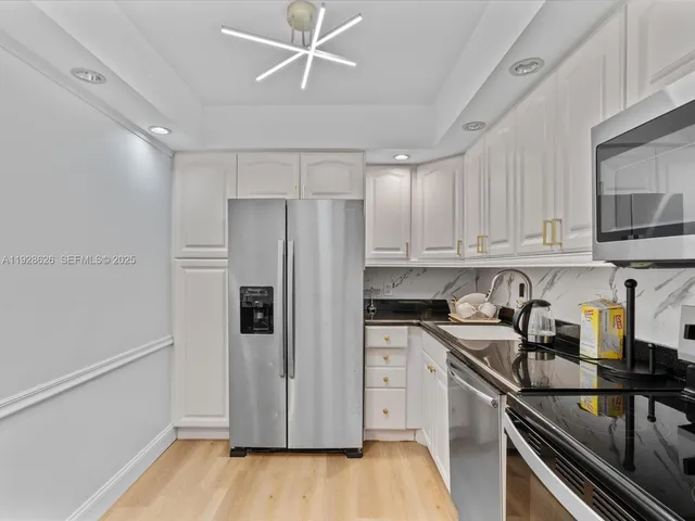 a kitchen with stainless steel appliances a refrigerator a sink and wooden floors