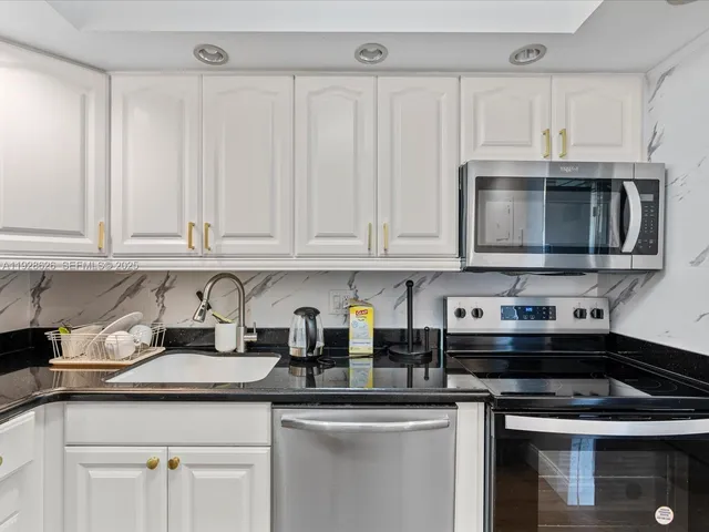 a kitchen with stainless steel appliances granite countertop a sink a stove a microwave and cabinets