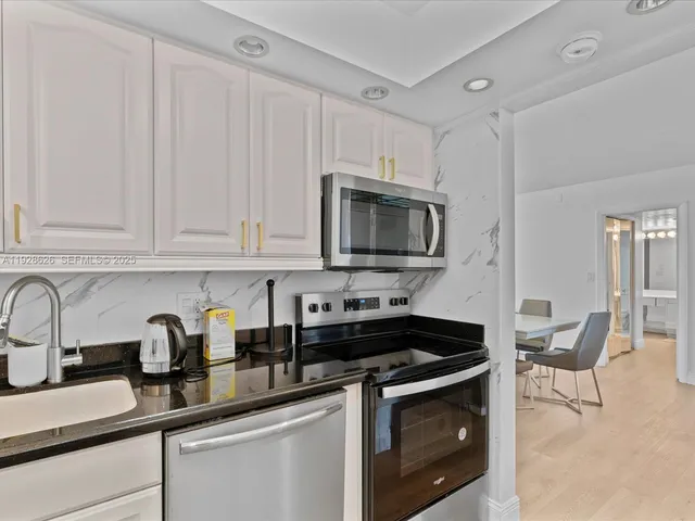 a kitchen with stainless steel appliances granite countertop white cabinets a sink and a stove