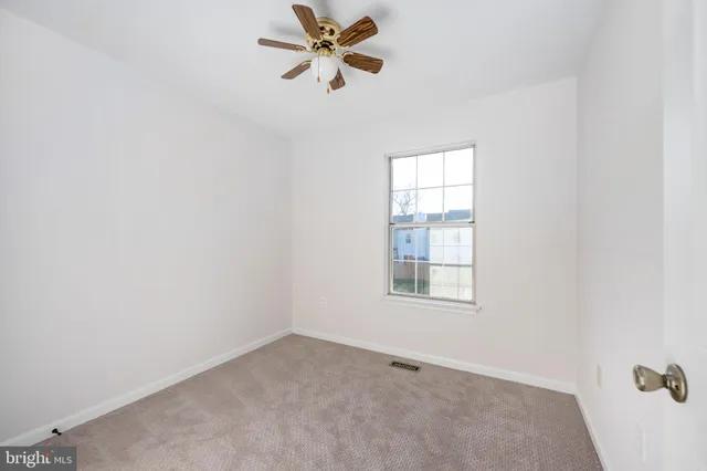an empty room with a window and a fan