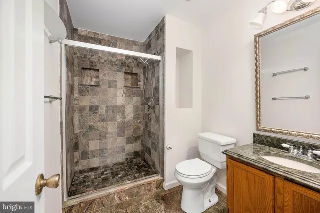 a bathroom with a granite countertop sink a toilet and shower
