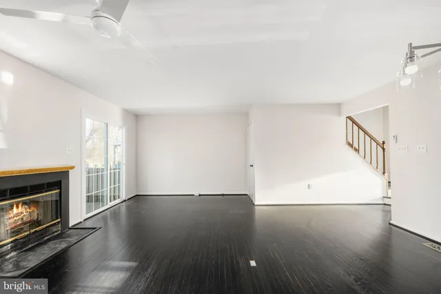 an empty room with wooden floor fireplace and windows
