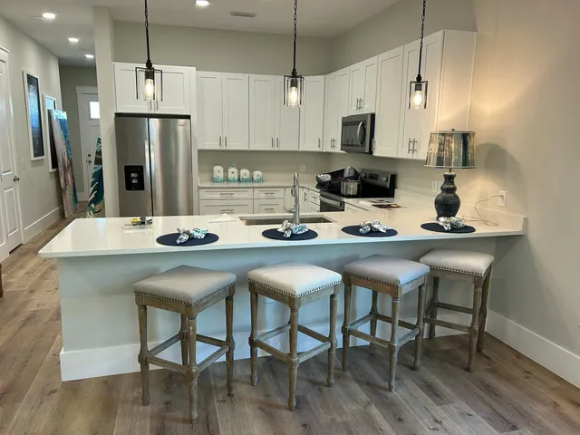 a kitchen with stainless steel appliances granite countertop a dining table chairs refrigerator and microwave