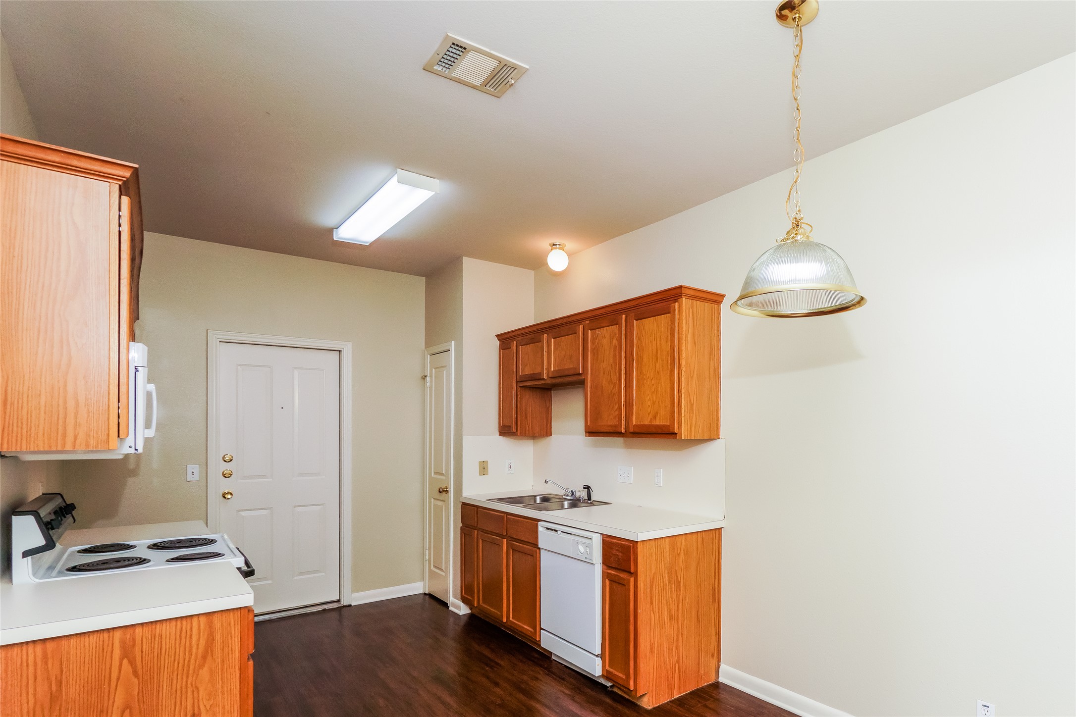 2403 Curry Loop Round Rock, TX 78664 - Photo 6 of 16 Kitchen with wood finish cabinets, white appliances, light countertops, dark wood-style floors, and pendant lighting
