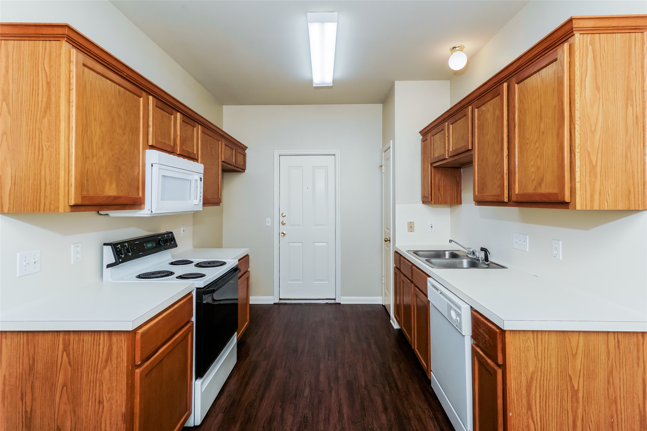 2403 Curry Loop Round Rock, TX 78664 - Photo 7 of 16 Kitchen featuring white appliances, light countertops, dark wood-type flooring, and wood finish cabinets
