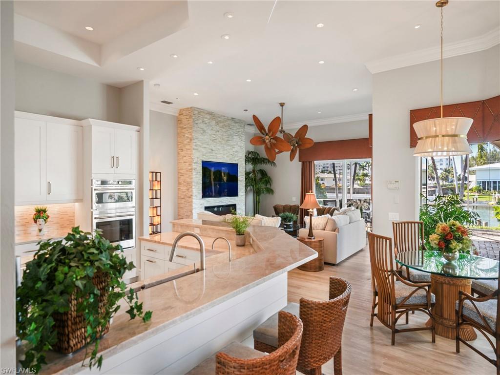 216 Springline Drive Naples, FL 34102 - Photo 22 of 46 Kitchen with white cabinetry, light wood-style flooring, light stone counters, recessed lighting, and a stone fireplace