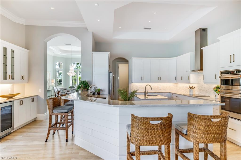 216 Springline Drive Naples, FL 34102 - Photo 25 of 46 Kitchen with a kitchen bar, arched walkways, white cabinetry, and ornamental molding