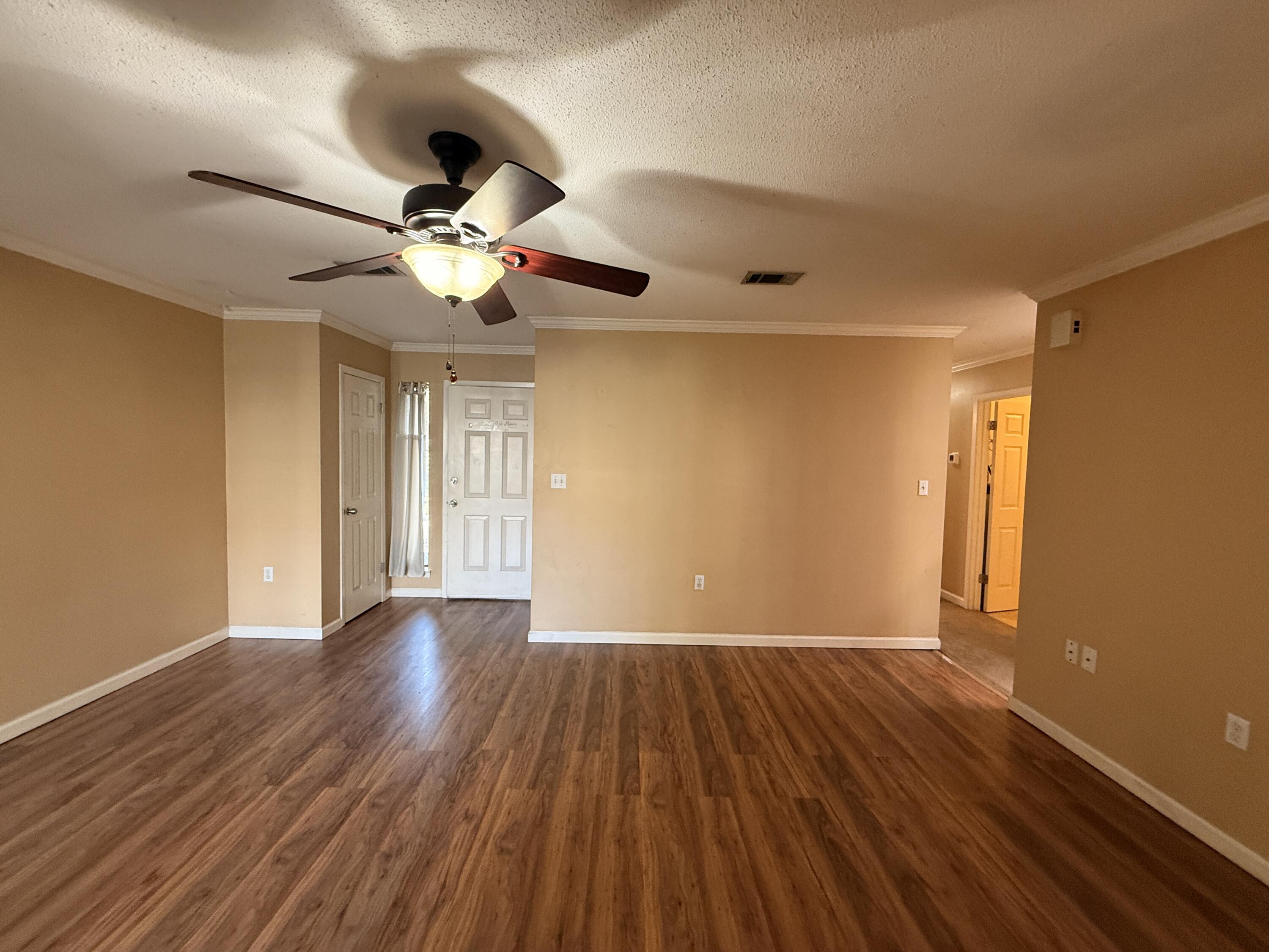 1054 9th Street Shalimar, FL 32579 - Photo 12 of 45 a view of an empty room with wooden floor and a ceiling fan