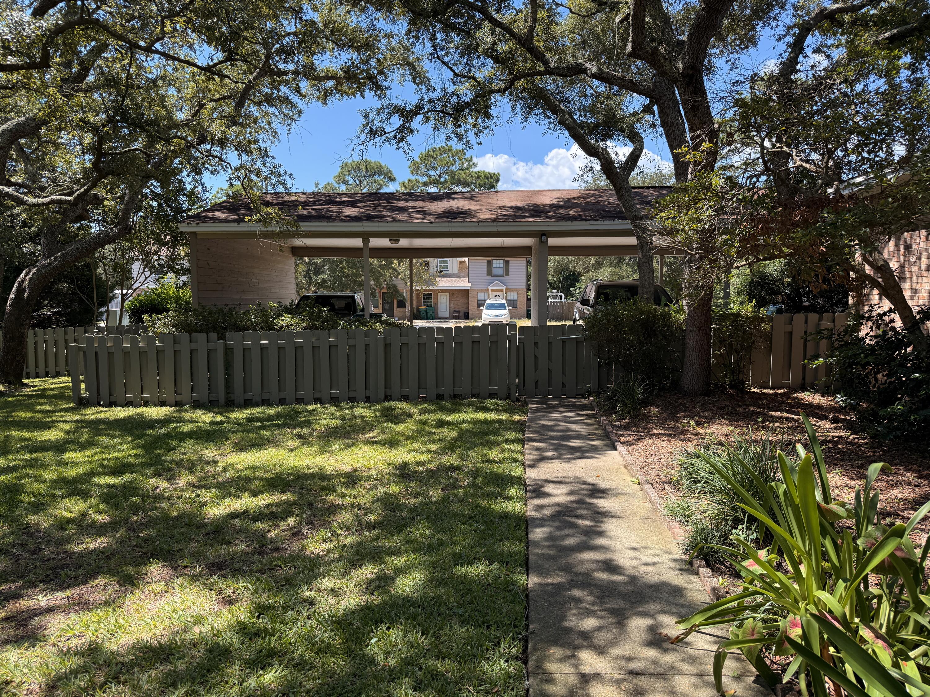 1054 9th Street Shalimar, FL 32579 - Photo 6 of 45 a view of a backyard with large trees and wooden fence