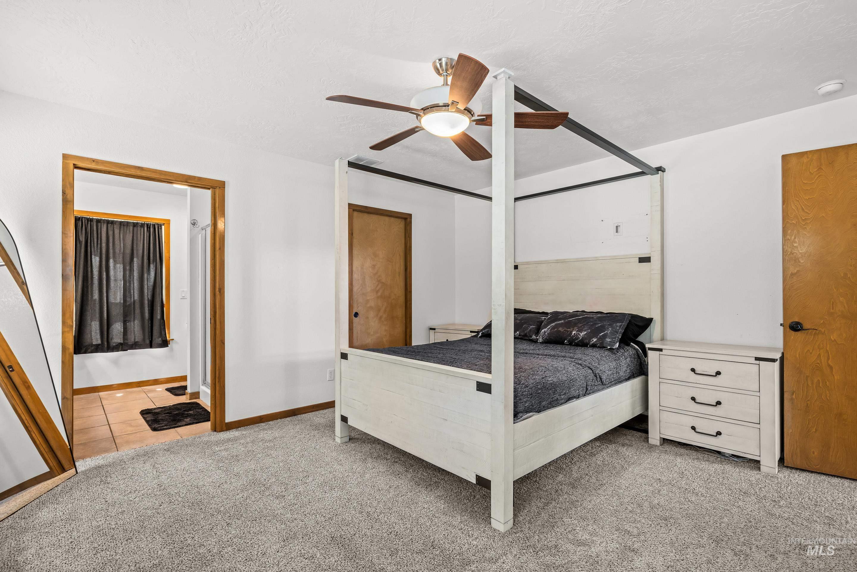 92 Cruickshank Road Horseshoe Bend, ID 83629 - Photo 22 of 50 Carpeted room with a ceiling fan, featuring a wood-trimmed doorway leading to a tiled area with a window