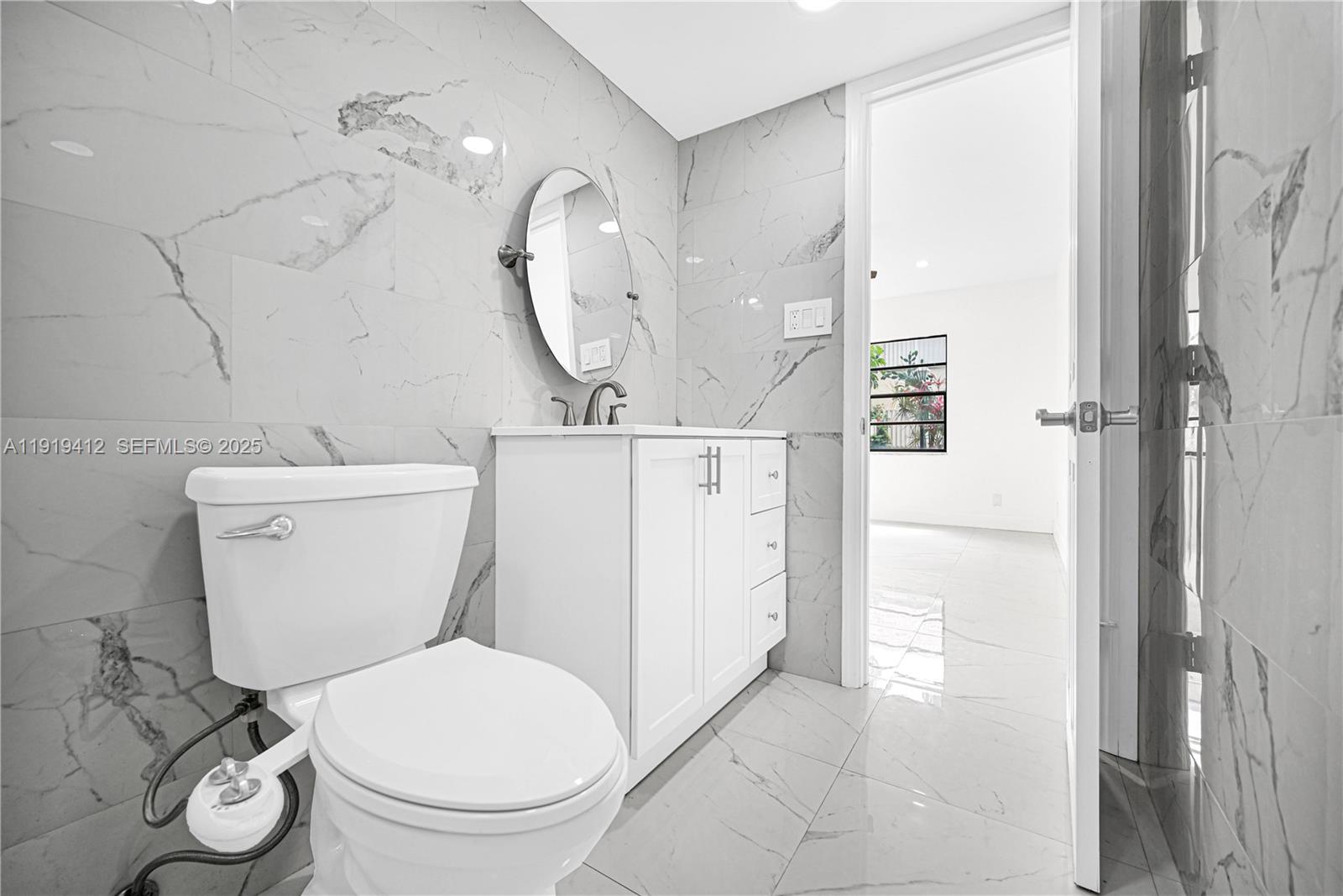 132 South Cypress Road, Unit 518 Pompano Beach, FL 33060 - Photo 26 of 60 a white toilet sitting next to a bathroom sink and a mirror