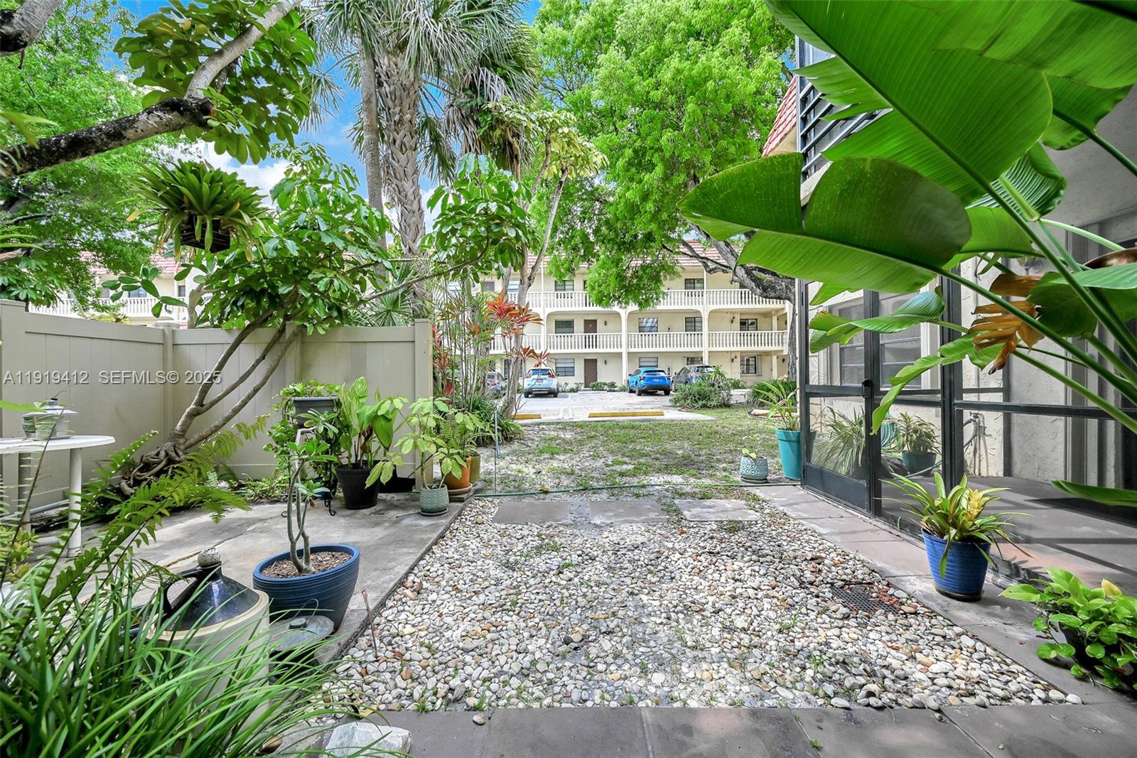 132 South Cypress Road, Unit 518 Pompano Beach, FL 33060 - Photo 3 of 60 a view of a backyard with potted plants and a large tree