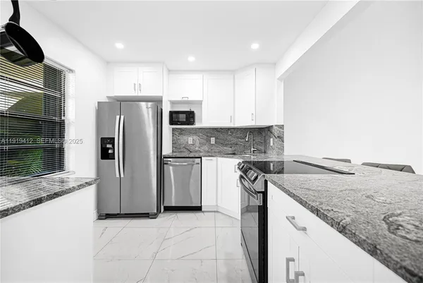 a kitchen with stainless steel appliances granite countertop a refrigerator and a stove