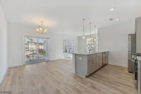 a kitchen with stainless steel appliances granite countertop a stove a sink a refrigerator and white cabinets with wooden floor